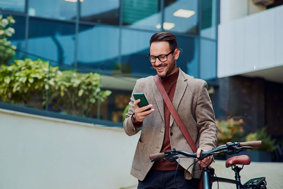 A man with a bicycle smiling at his phone